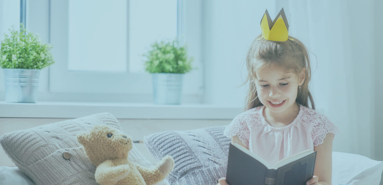 Girl reading book with teddy bear