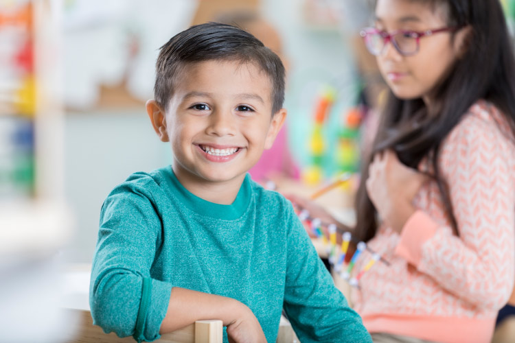 Dark-haired boy in teal shirt smiles with strong teeth fortified with fluoride in Tyler, TX