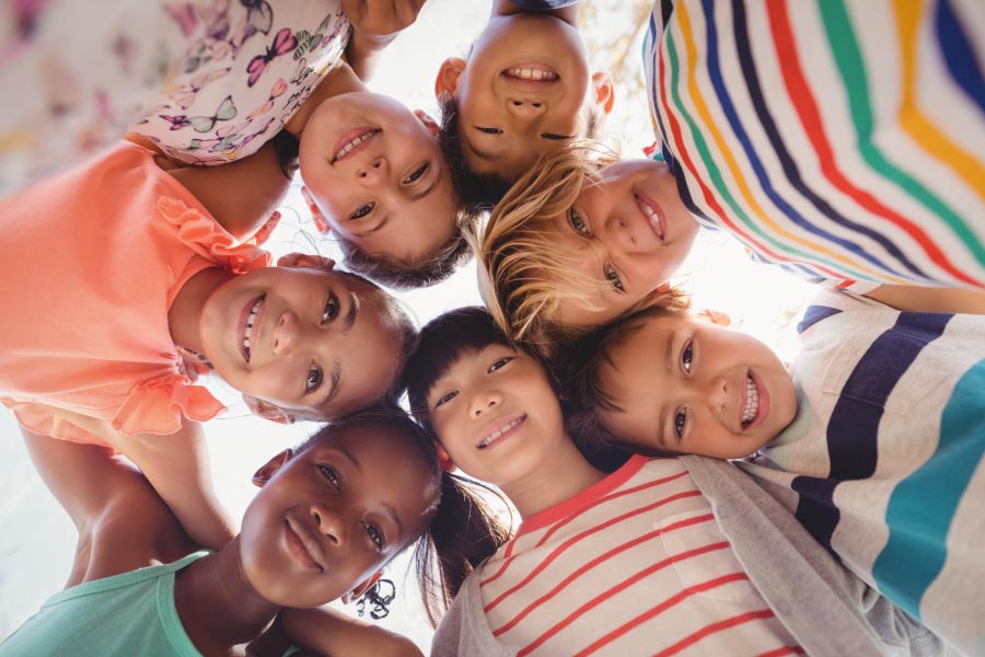 Looking up into the faces of a group of children huddled together after visiting their pediatric dentist