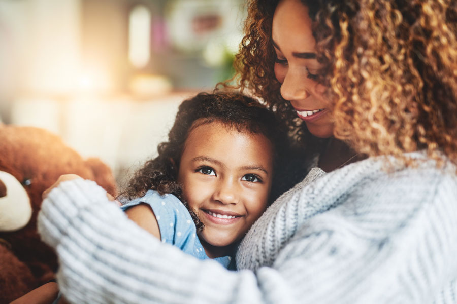 Curly-haired mom and daughter snuggle after eating a healthy snack