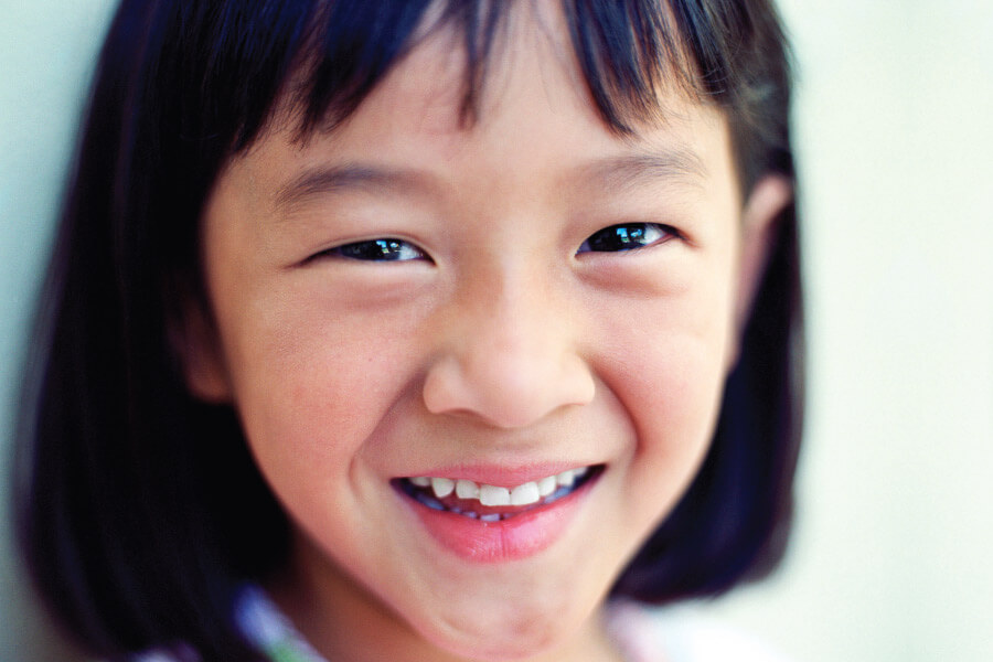 Closeup of a little girl smiling because she feels relaxed at the dentist with pediatric dental sedation
