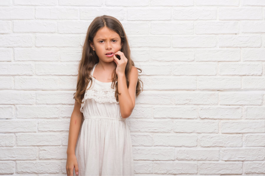 Brunette girl cringes in pain and touches her cheek because she needs root canal therapy in Tyler, TX