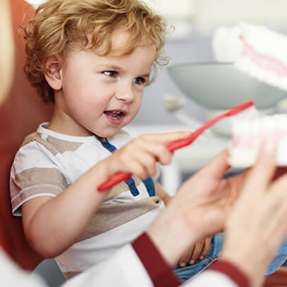 young boy learning how to brush his teeth